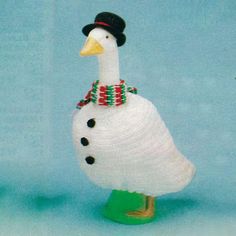 a white duck with a black hat and scarf on it's head is standing in front of a blue background