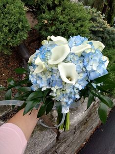 a bouquet of blue and white flowers being held by someone