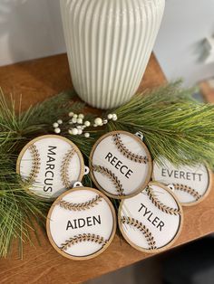 four decorated baseball cookies sitting on top of a wooden table next to a white vase