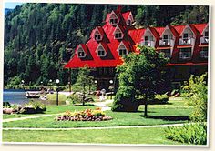 a large red building sitting on top of a lush green field next to a lake