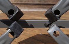 two metal bars with holes in them on a wooden floor next to a fence and wood planks