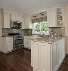 a kitchen with white cabinets and an island in front of a stove top oven next to a window