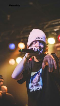 a man holding a microphone up to his mouth while standing in front of a crowd