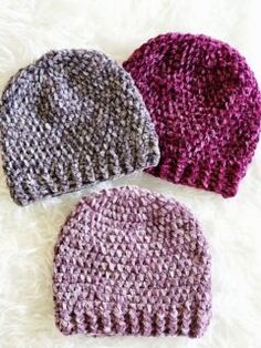 three crocheted hats laying on top of white fur