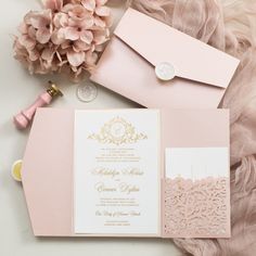 pink and gold wedding stationery with envelopes, flowers, and other items on a furnishing