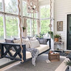 the porch is decorated with black and white decor, including a swing bed that has pillows on it