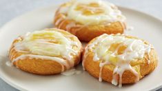 three lemon muffins with icing on a white plate