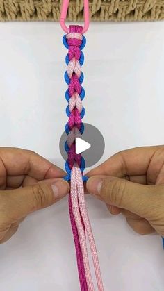 two hands are holding a pink and blue piece of yarn