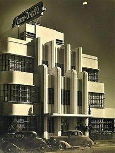 an old black and white photo of a building with cars parked in front of it