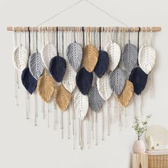 a wall hanging with several different colored leaves on it and a wicker basket next to it