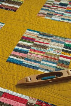 a close up of a quilt with a wooden stapler on the top and yellow background