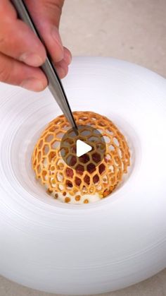 a person cutting into a piece of food on top of a white plate