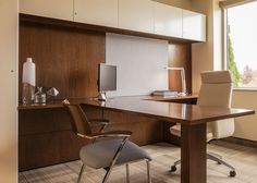 an office with a desk and chair next to a large window in the middle of it