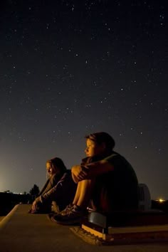 two people sitting on a bench watching the stars