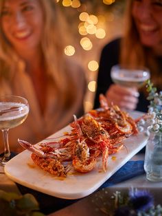 two women sitting at a table with plates of food and drinks in front of them