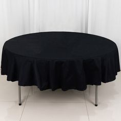 a round table with a black cloth on it and white walls in the back ground