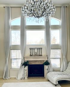 a living room filled with furniture and a chandelier hanging from the ceiling over a fire place