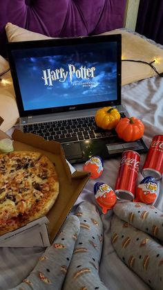 a laptop computer sitting on top of a bed next to pizza and orange juices