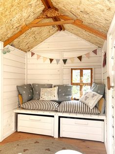 a room that has some drawers under the roof and pillows on the bench in front of it