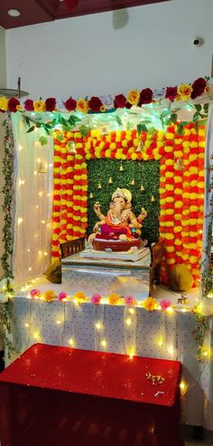 an idol is displayed in front of a decorated stage with flowers and garlands on it