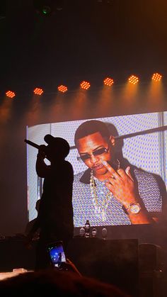 a man standing in front of a large screen on top of a stage holding a microphone