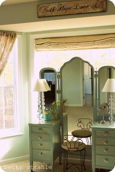 a bedroom with a dresser, mirror and lamp on it's side in front of a window