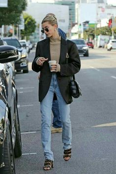 a woman walking down the street while holding a coffee