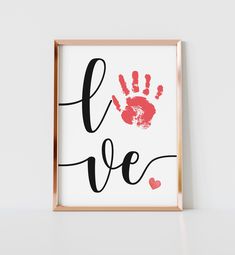 a framed print with the words love and handprinted red hearts in black ink