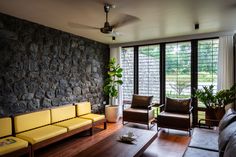 a living room with two couches, chairs and a stone wall in the background