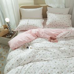 an unmade bed with pink comforter and pillows