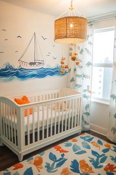 Cozy baby room with an explorer theme. Features a white crib, ocean mural, nautical mobile, and colorful curtains and rug. Perfect nursery inspo. Nursery Unique, Colorful Nursery Decor, Cozy Nursery, Unique Nursery, Stylish Nursery, Creative Storage Solutions