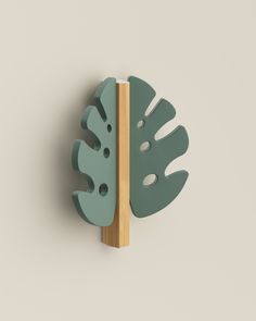 a green leaf shaped object mounted on a wall next to a wooden board with holes in it