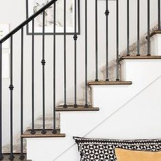 a black and white pillow sitting on top of a wooden floor next to a stair case