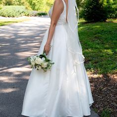 a woman in a wedding dress is standing on the street with her veil over her head