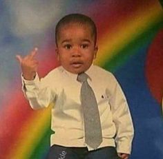 a young boy wearing a tie standing in front of a rainbow background