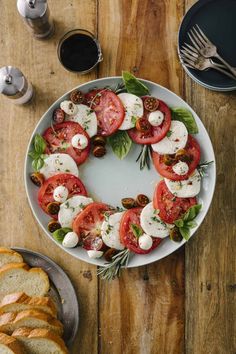 a white plate topped with sliced tomatoes and mozzarella on top of a wooden table