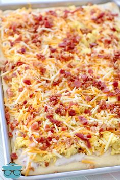 an uncooked casserole with cheese and bacon on it in a pan