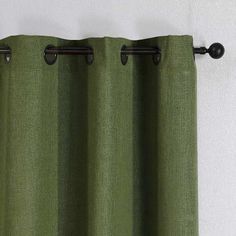 a green curtain hanging on the side of a white wall with black metal rods and an iron rod