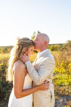 a bride and groom kissing in the field