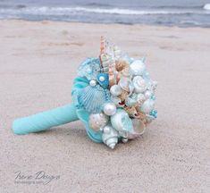 a bridal bouquet on the beach with seashells and pearls