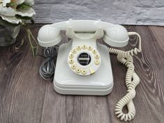 an old - fashioned phone is sitting on the floor next to a vase with flowers