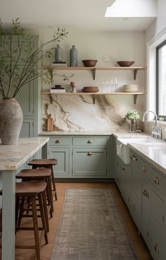 a kitchen with green cabinets and marble counter tops, along with wooden stools in front of the sink