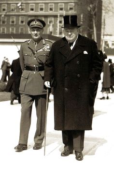 two men in uniform standing next to each other on a sidewalk with buildings in the background