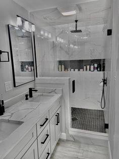 a white bathroom with two sinks and a shower stall in the corner, all decorated in black and white marble