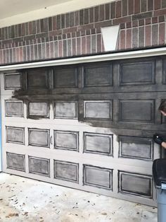 a man painting the side of a garage door