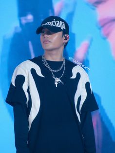 a male in a black and white shirt is wearing a baseball cap with chains on it