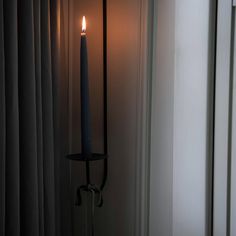 a candle is lit in the corner of a room next to a window with curtains