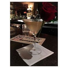 a rose sitting on top of a table next to a martini