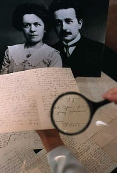 a person holding a magnifying glass looking at an old letter with two people on it