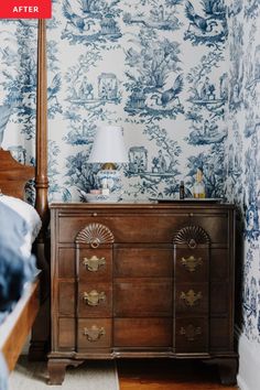 a bedroom with blue toiler wallpaper and a wooden dresser in the corner